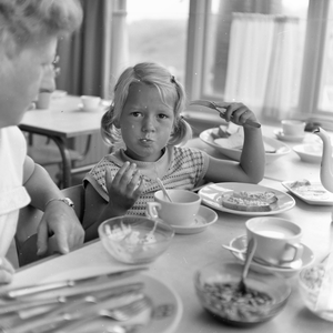 841942 Afbeelding van een meisje tijdens het ontbijt in het vakantieoord Westerduin te Wijk aan Zee.